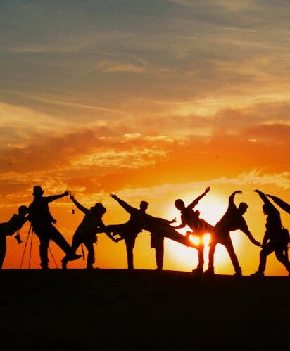 Group of people silhouetted against a vibrant sunset, showcasing unity and joy.